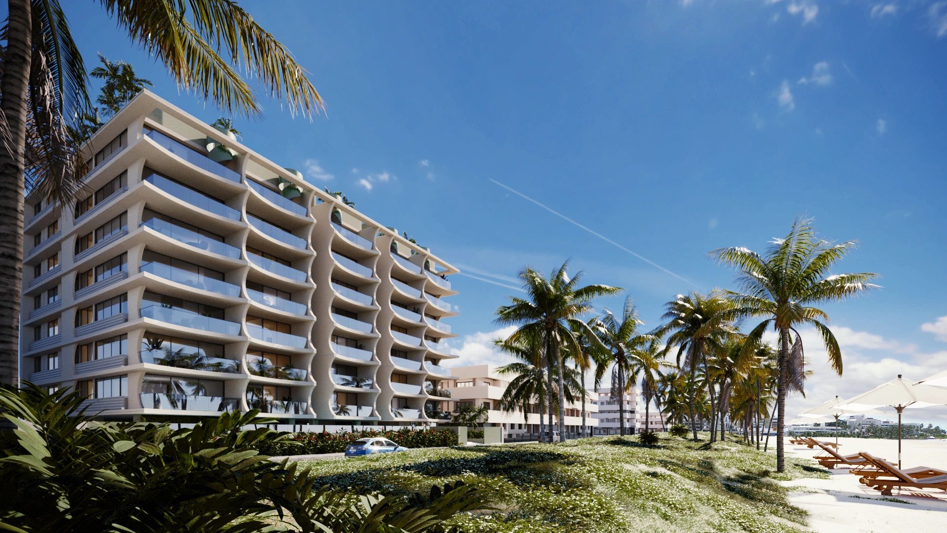 Modern beachfront building with palm trees and lounge chairs under umbrellas.