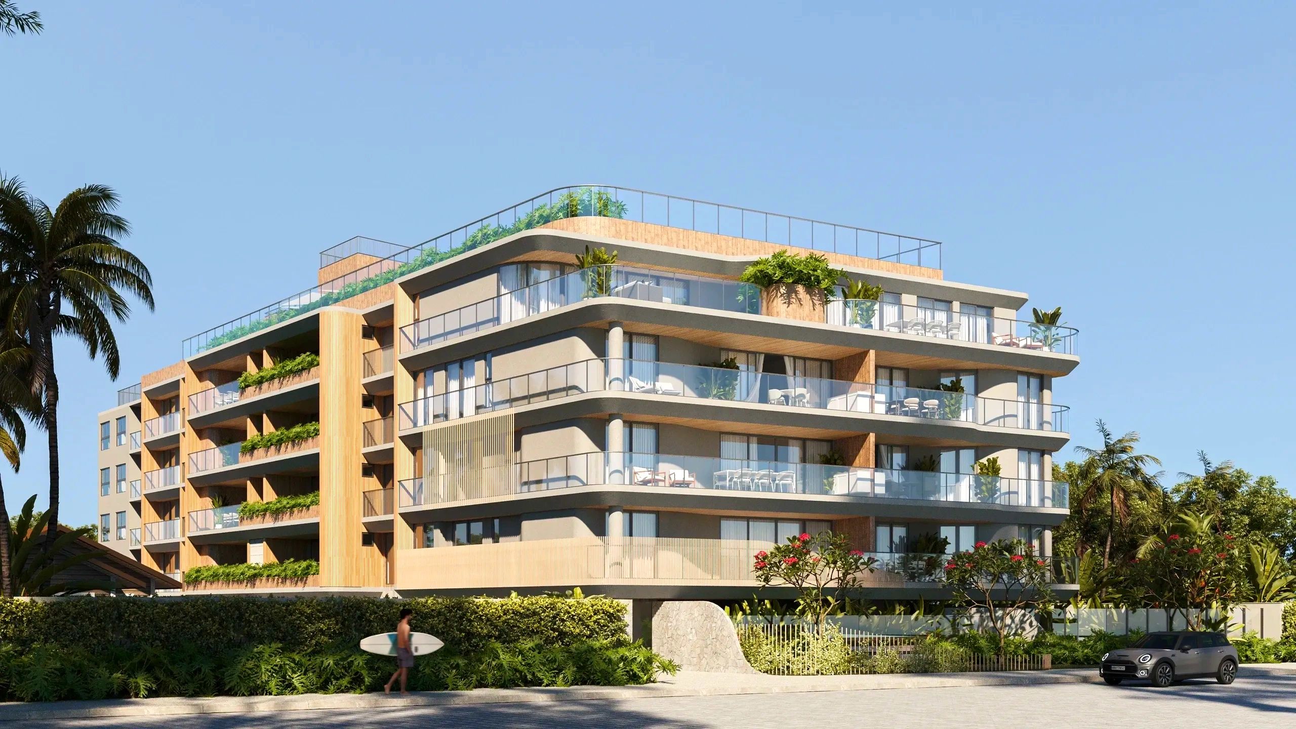 Modern apartment building with glass balconies and greenery under a clear blue sky.