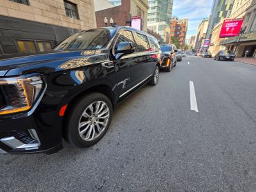 Luxury black SUVs parked on a city street.
