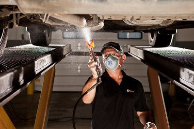 Worker spraying under a vehicle.