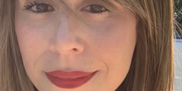 Close-up of a woman with light brown hair and red lipstick.