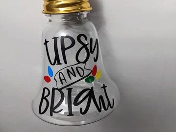 Clear bell-shaped container with "Tipsy and Bright" text and colorful decorations.