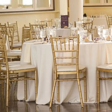 Elegant round tables with gold chairs set for a formal event.