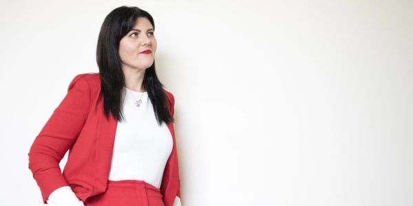 Confident woman in a red suit against a white background.
