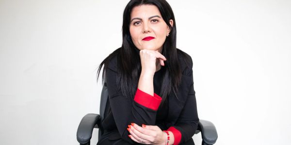 Woman in black and red outfit sitting confidently.