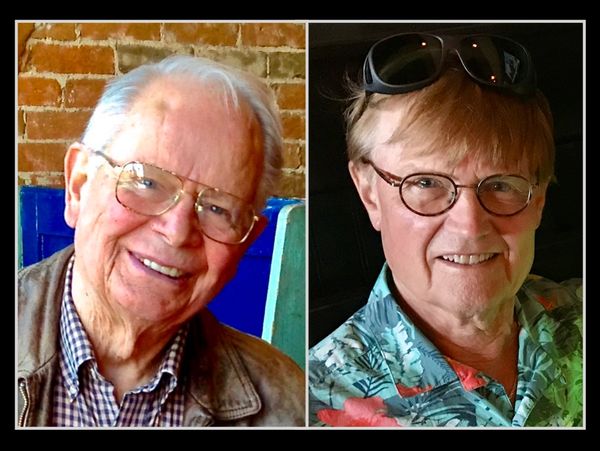 Two elderly men smiling, one with glasses and a leather jacket, the other with round glasses and sunglasses on his head.