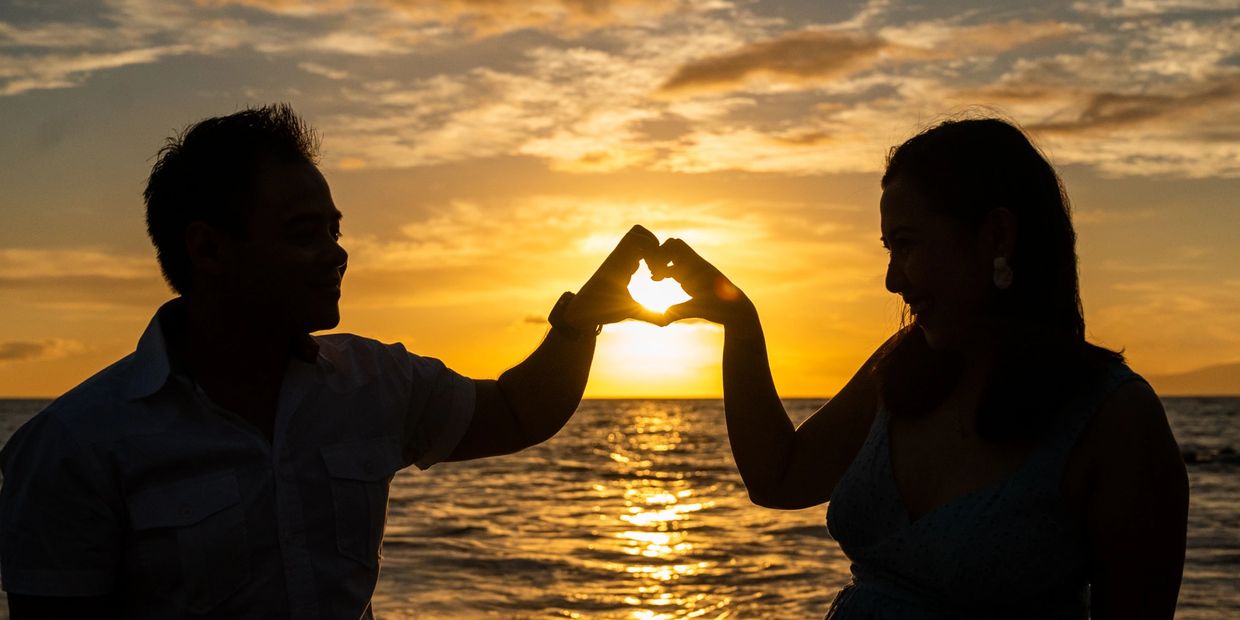 Couple forming heart in the sun with their hands