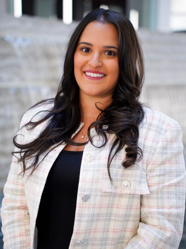 Smiling woman in a plaid jacket with long dark hair.