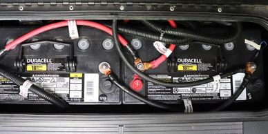 Two connected Duracell 12V batteries with red and black cables.