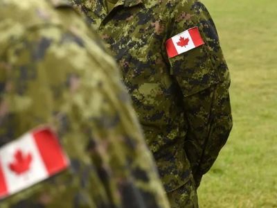 Canadian soldiers in camouflage uniforms with flags on sleeves.