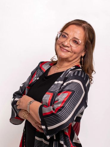 Smiling woman in glasses and a patterned black, red, and white outfit poses confidently.