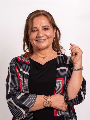 Smiling woman in a patterned shawl and black dress posing confidently.