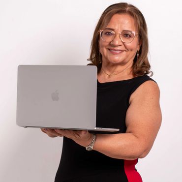 Smiling woman holding an open laptop, wearing glasses and a black dress with a red stripe.