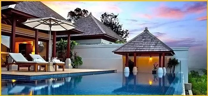 Infinity pool with poolside lounge chairs under an umbrella.