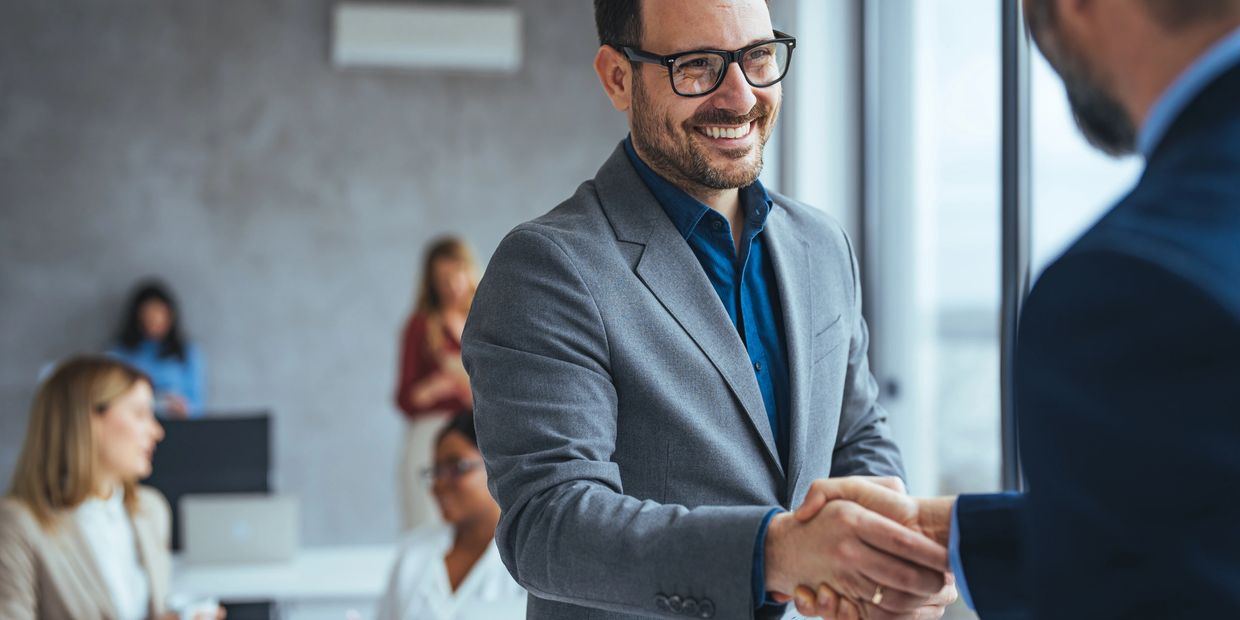 Two men shaking hands in a business setting.