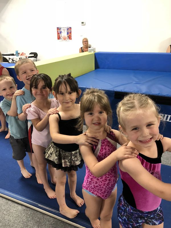 Children lined up in gymnastics outfits smiling.