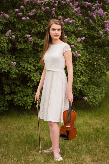 Girl in a white dress holding a violin.