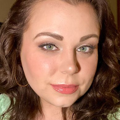 Close-up of a woman with curly hair and green eyes.