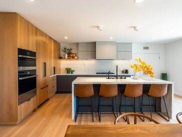 Modern kitchen with wooden cabinets and a white island with brown bar stools.