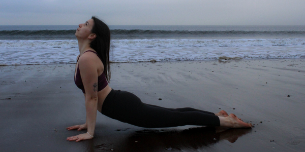 Woman practicing yoga on a beach during early morning.