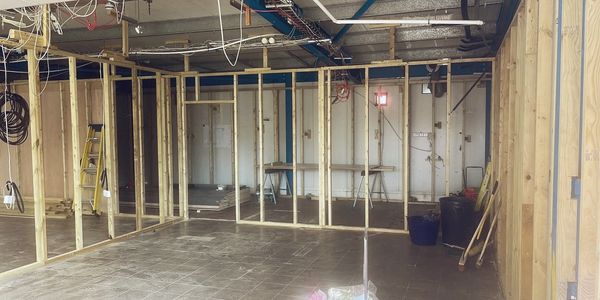 Interior construction with wooden framing and exposed ceiling wires.