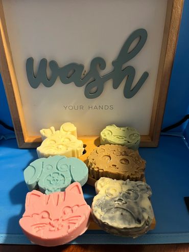 Colorful animal-shaped soaps with a 'wash your hands' sign in the background.