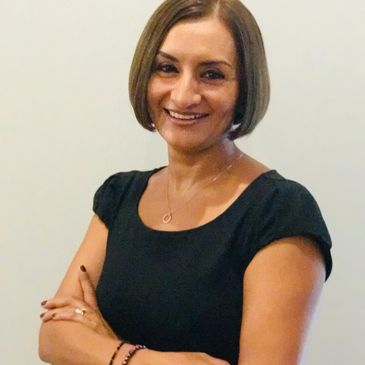Woman with short hair smiling confidently with arms crossed.