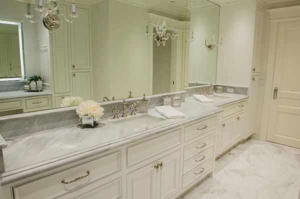 Double sinks and marble counters with chandeliers. 