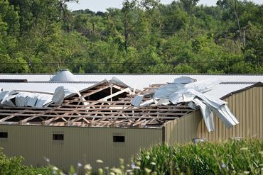 Metal roof torn off commercial building, exposing wood trusses after storm damage
