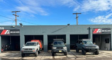 Three Toyota 4Runners parked outside Auto Worx service bays under a blue sky.