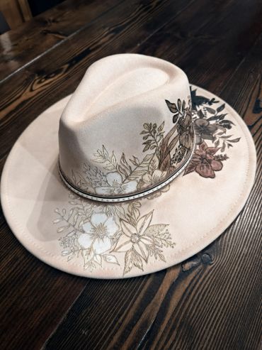 Beige floral embroidered hat on wooden table.