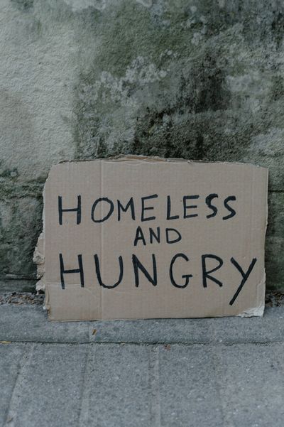 homeless sign against a wall