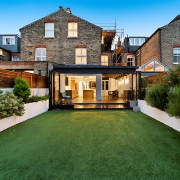 Modern house with glass extension and green lawn.