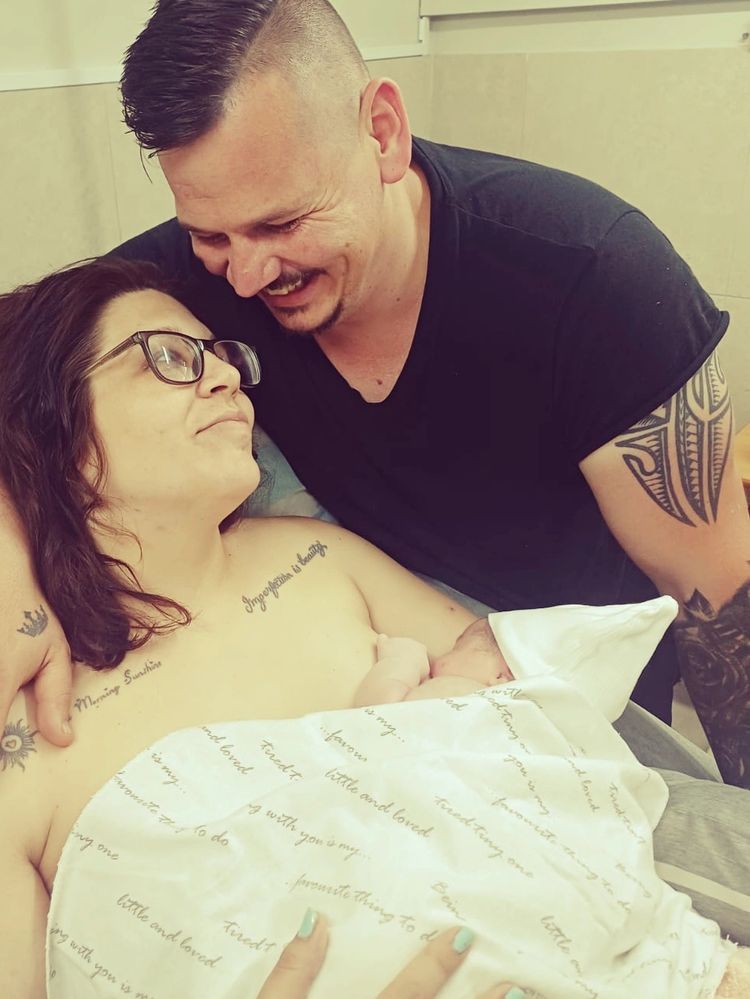 New parents sharing a tender moment with their newborn baby.