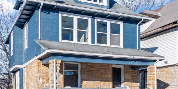 Two-story blue and stone house with front porch.