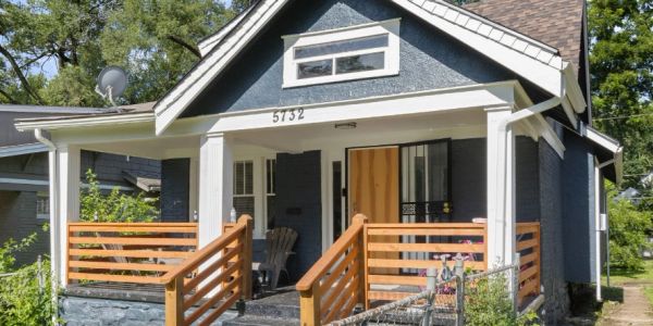 Small blue house with wooden porch railings.