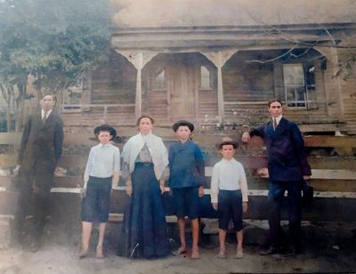 Foto antigua de familia frente a una casa de madera.