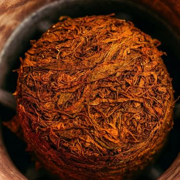 Close-up of a tightly packed ball of dried tobacco leaves.