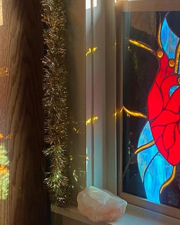 Sunlight shining through stained glass and tinsel on a windowsill.