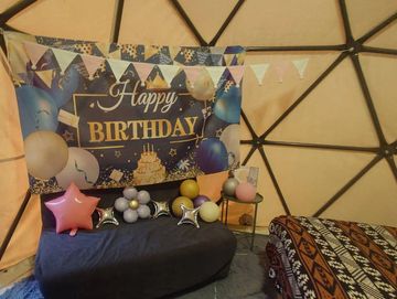 Cozy birthday setup with balloons and decorations inside a dome tent.