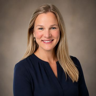 Professional portrait of a smiling woman with blonde hair.