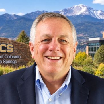 Smiling man outdoors with mountain backdrop.