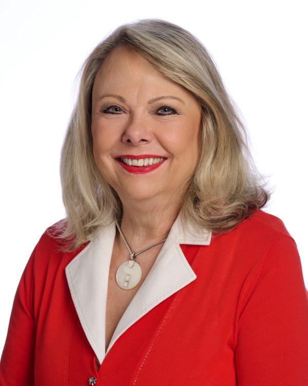 Smiling woman in red jacket and white shirt.