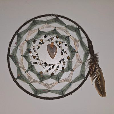 Handcrafted dreamcatcher with feathers and beads hanging on a wall.