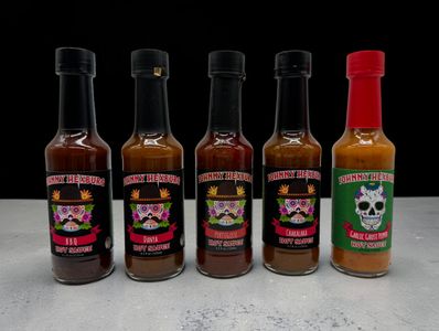 Five bottles of Johnny Hexburn hot sauces with colorful skull labels.