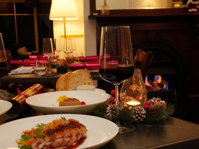 Cozy dining setup with wine and gourmet dishes near a fireplace.