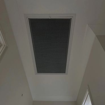 Large ventilation grille on a white ceiling above a doorway.