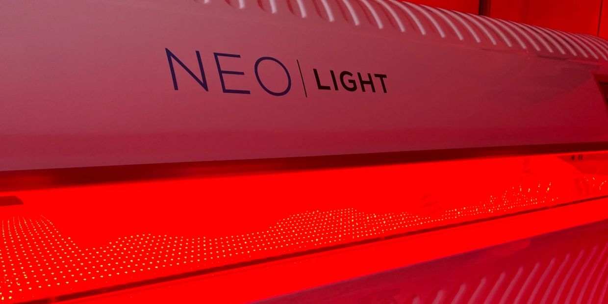 Close-up of a NEO Light tanning bed glowing red inside.