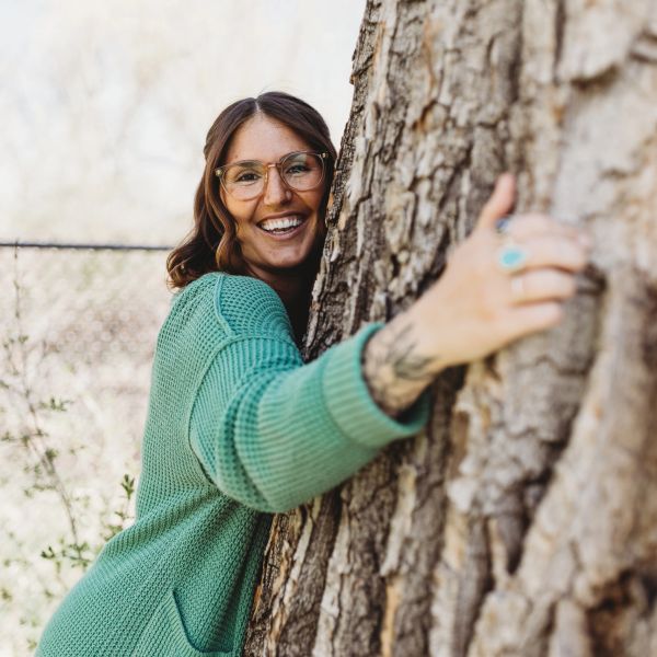 Woman hugging a tree and smiling.