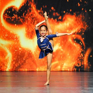 a dancer in a leg hold in a blue costume on the ignite dance competition stage